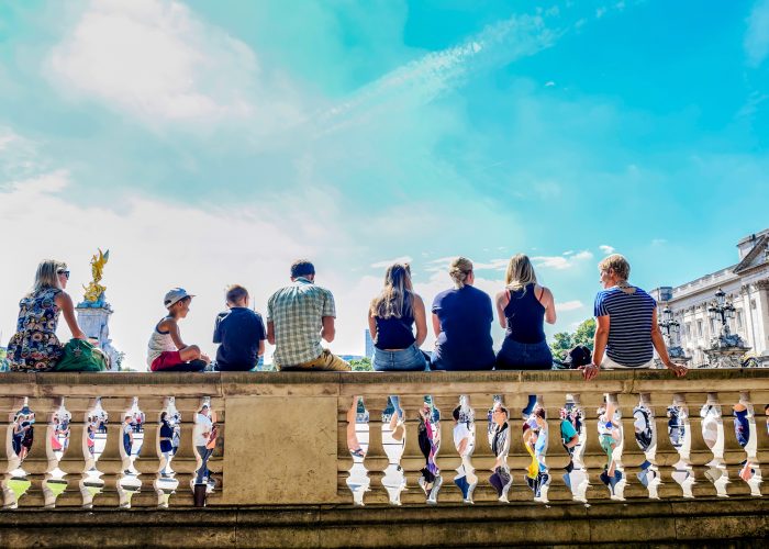 People sitting on wall to watch the Changing of the Guard outside Buckingham Palace in London