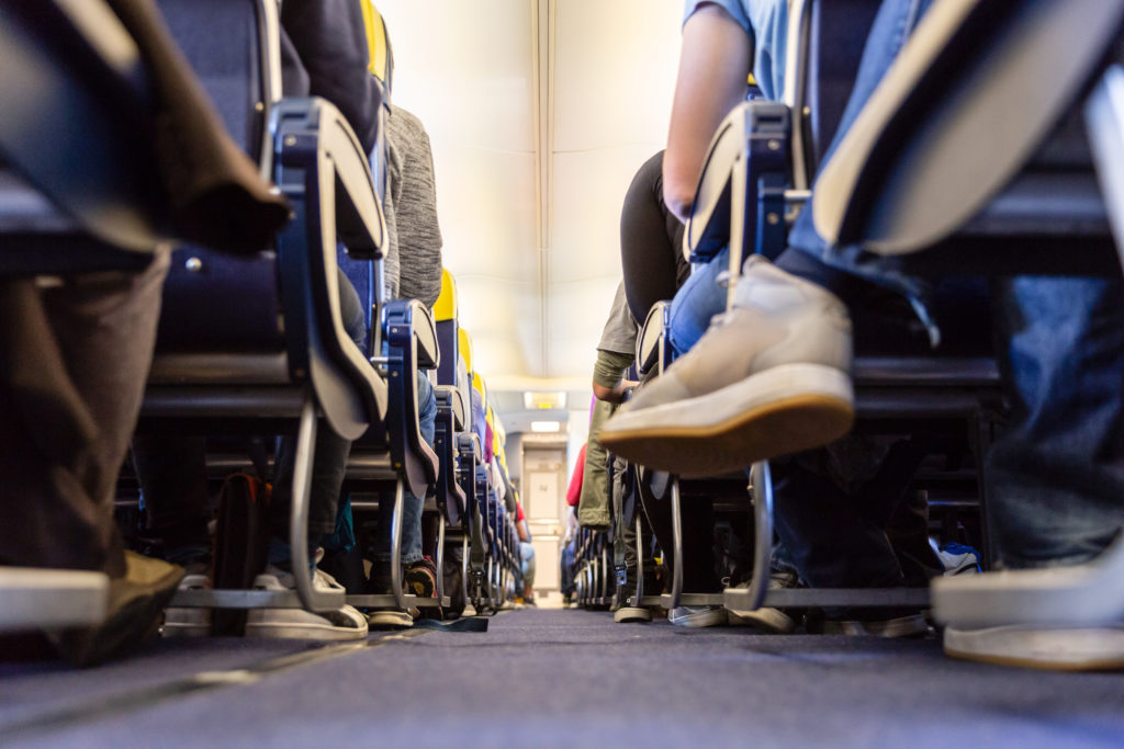Low angle view of airplane aisle showing passenger's shoes