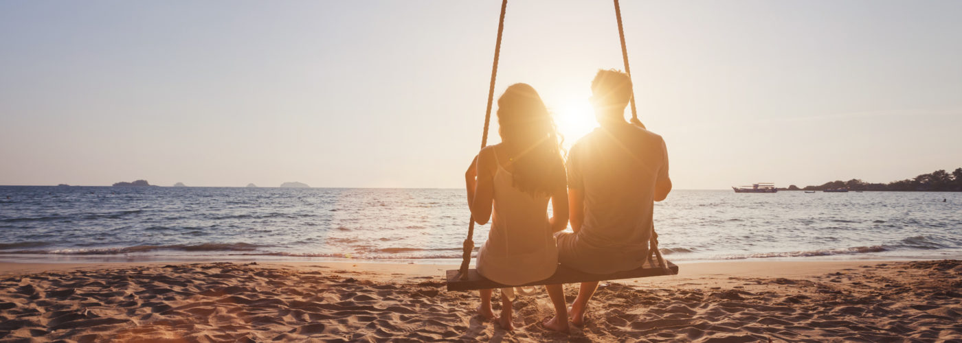 Silhouette of couple on swing on beach
