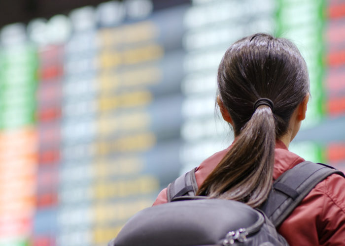 Woman with backpack reading the arrivals board at an airplane