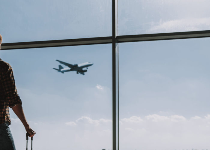 Man watching plane take off from airport window
