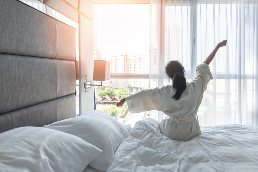 Woman waking up and stretching in city hotel room