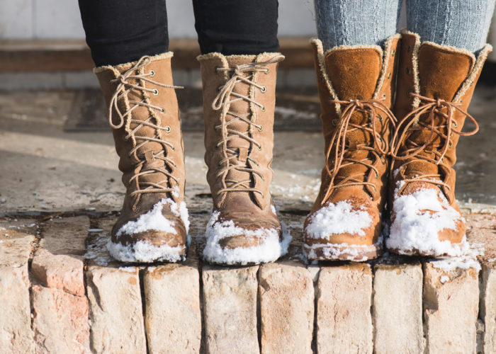Close-up of people wearing winter boots with snow on them
