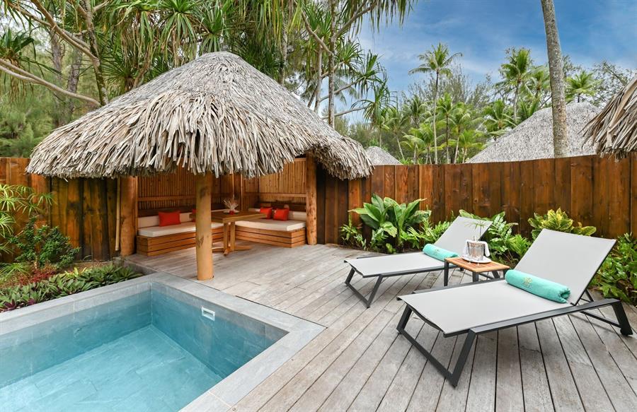 Lounge chairs and straw awnings by the pool at Le Bora Bora by Pearl Resorts